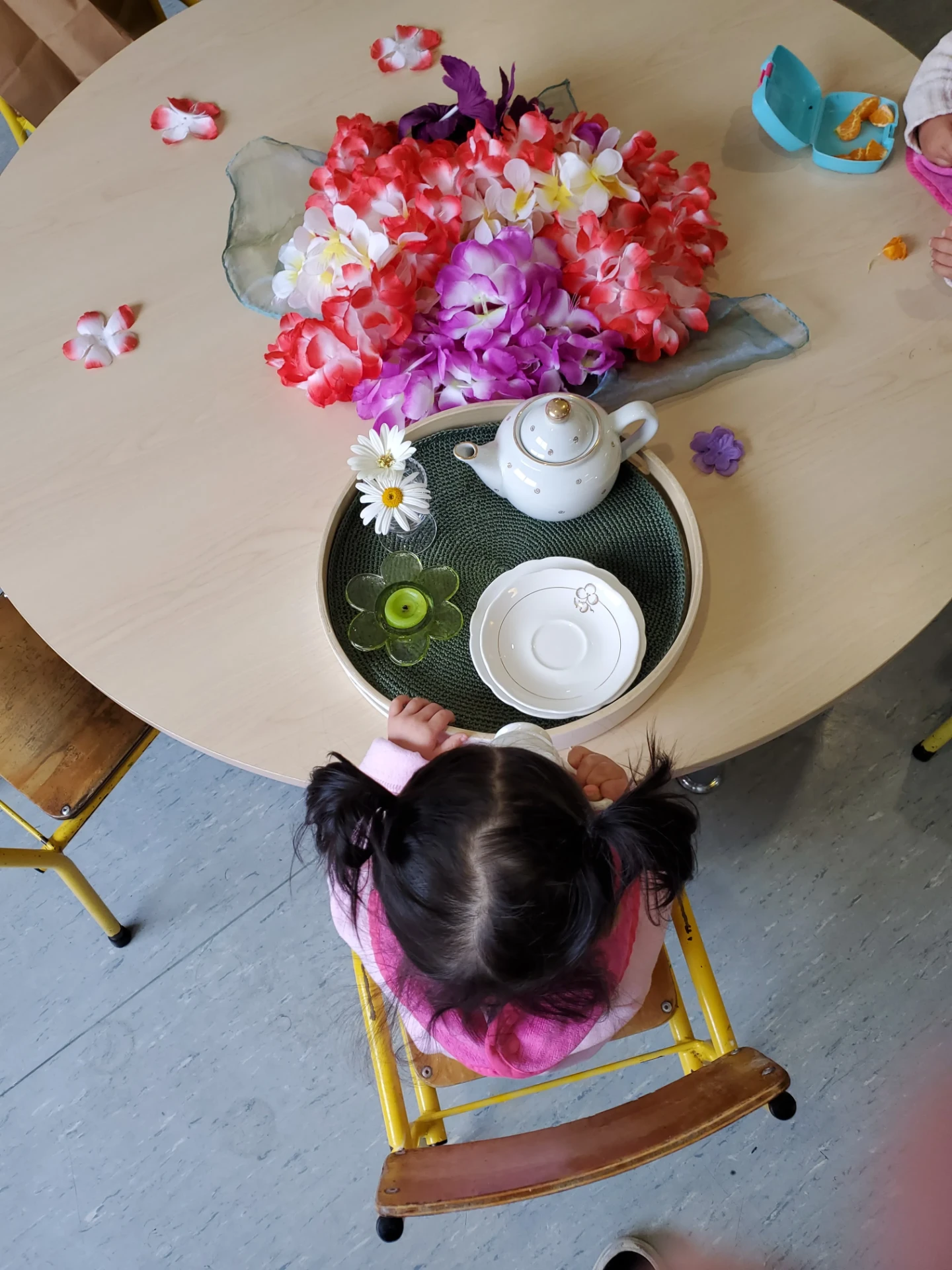 A child at Growing Minds enjoying a flower tea ritual at a low table